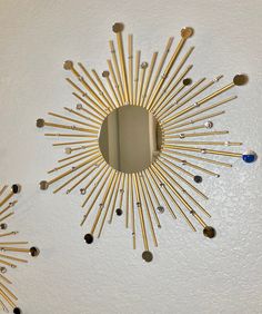 a mirror that is on the side of a wall with some gold sticks sticking out of it