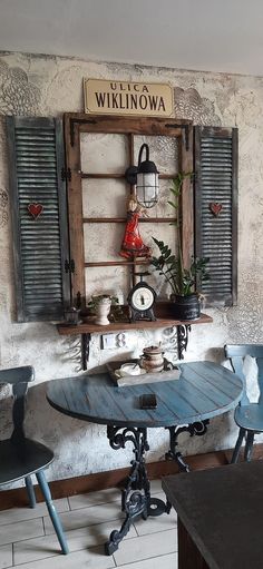 a table and chairs in a room with old shutters on the wall above it