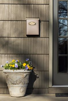 a potted planter with yellow and purple flowers in front of a gray door