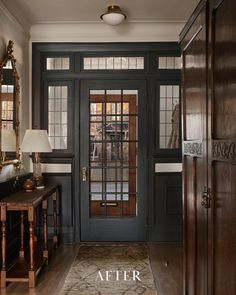 an entry way with black doors and wood floors, along with a rug on the floor