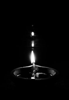 a candle is lit in the dark on a black background with no one around it