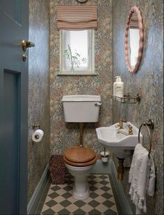 a bathroom with a toilet, sink and mirror in it's center wallpaper