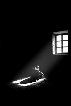 a person sitting on the floor in front of a window with light streaming through it