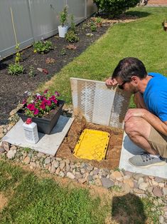 a man kneeling down next to a planter filled with dirt and yellow squares on the ground