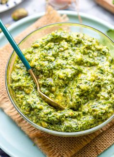 a bowl filled with green sauce on top of a blue plate