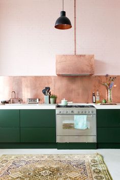 a kitchen with green cabinets and an area rug on the floor in front of it