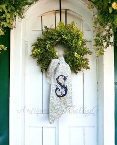 a door with a wreath on it and a monogrammed tie hanging from the front