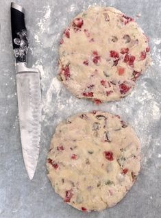 two pizzas sitting on top of a table next to a knife