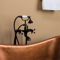 an old fashioned copper bathtub with black faucet and hand shower head in the corner