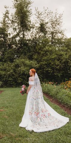 a woman in a wedding dress standing on the grass