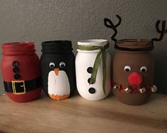 four painted mason jars decorated to look like christmas characters