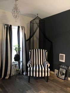 a black and white striped chair sitting in front of a window with drapes on it