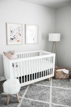 a white crib in the corner of a room with two pictures on the wall