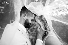 black and white photo of a bride and groom kissing under the veil on their wedding day