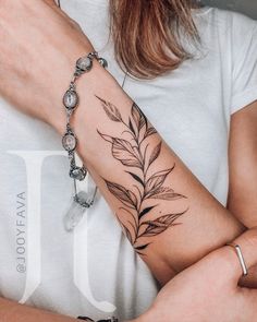 a woman's arm with a leaf tattoo on the left side of her arm