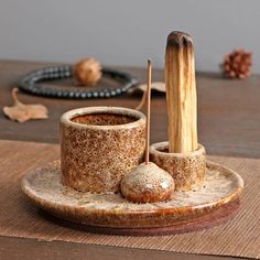 a wooden table topped with a cup and saucer filled with food next to a beaded bracelet