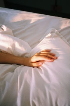 a person laying in bed with their hand on the pillow