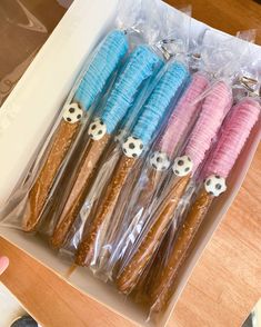 a box filled with candy covered in blue, pink and brown frosted pretzels