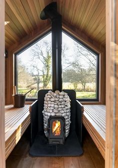 a wood burning stove sitting inside of a wooden cabin on top of a hard wood floor