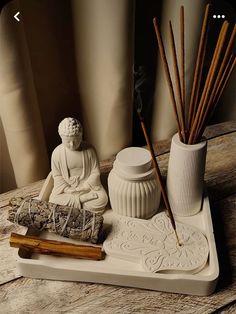 a white buddha statue sitting on top of a wooden table next to two vases