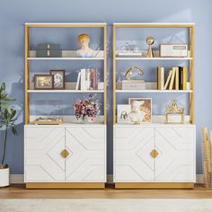 a white and gold bookcase with books on it next to a potted plant