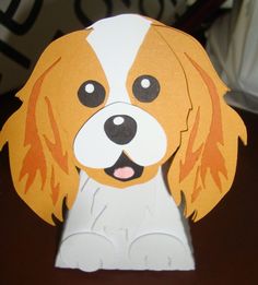 a brown and white dog sitting on top of a table next to a paper cutout