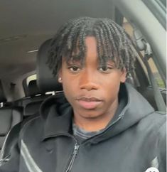 a woman with dreadlocks sitting in the back seat of a car looking at the camera