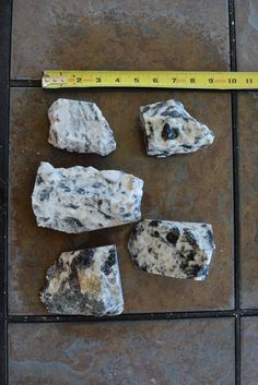 four rocks are shown with a measuring tape