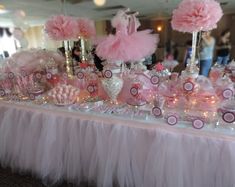 a table topped with lots of pink and white candy bar decorations on top of a table