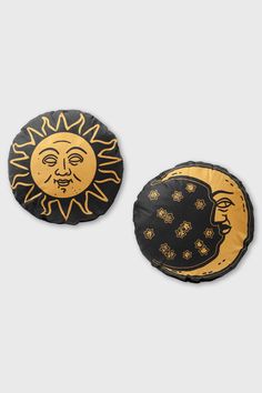 two black and yellow sun and moon pillows on a white background, one with gold details