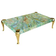 a coffee table with gold legs and a green marble design on the top, sitting in front of a white background