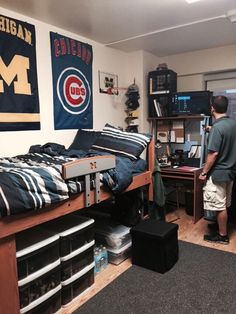 a man standing next to a bed in a room filled with furniture and sports memorabilia