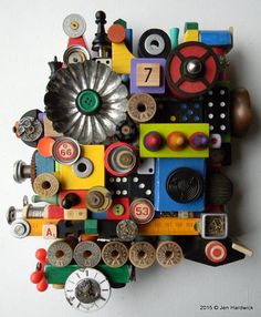 a sculpture made out of various types of toys and buttons on a white surface with the number seven written below it