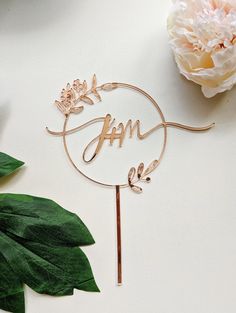 a cake topper with the word h m on it sitting next to some flowers