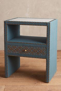 a small blue table with studded drawers