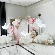 balloons are arranged in the shape of flowers and butterflies on a marble floor with a white pedestal