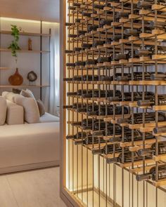 a living room filled with furniture and lots of wine bottles on the wall next to a white couch