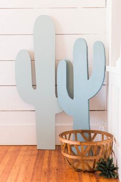 a wooden cactus sitting next to a basket on the floor in front of a white wall