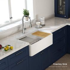 a kitchen with blue cabinets, white counter tops and an island style sink in the middle