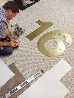 a man sitting on the floor next to a dog and cut out numbers with scissors