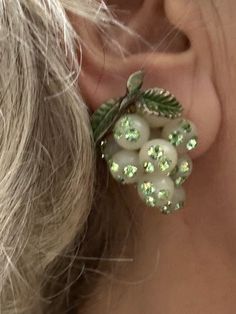 a close up of a person's ear wearing earrings with beads and leaves on them