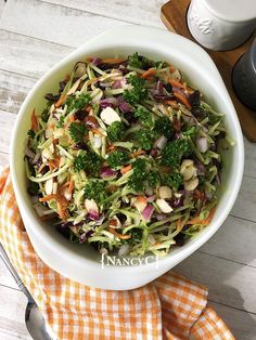 a white bowl filled with broccoli, carrots and other veggies