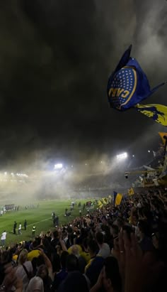 a stadium filled with people and flags under dark clouds