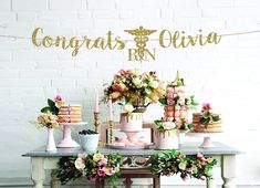 a table topped with cakes and flowers next to a sign that says congrats & olvia