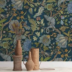 two vases sitting next to each other in front of a wall with flowers and birds on it