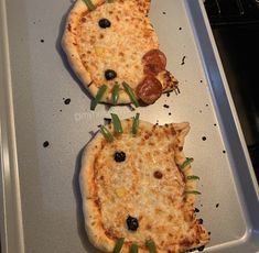 two pizzas that are sitting on top of a pan in the oven, one is shaped like a cat