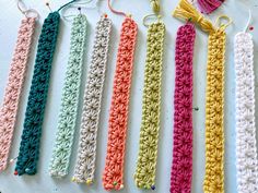 crocheted bookmarks lined up on a table with yarn in the shape of tassels