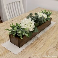 two wooden planters filled with white flowers on top of a table