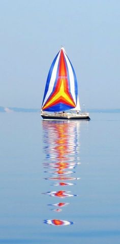 a colorful sail boat floating in the water