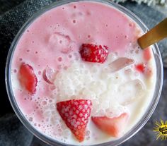 a close up of a drink with strawberries and milk in it on a table